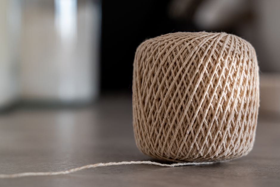 A close-up of a tan twine ball resting on a smooth surface, indoors.