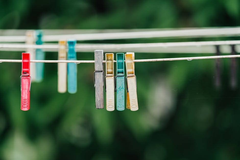 Close-up of colorful clothespins hanging on a laundry line outside with a green backdrop.