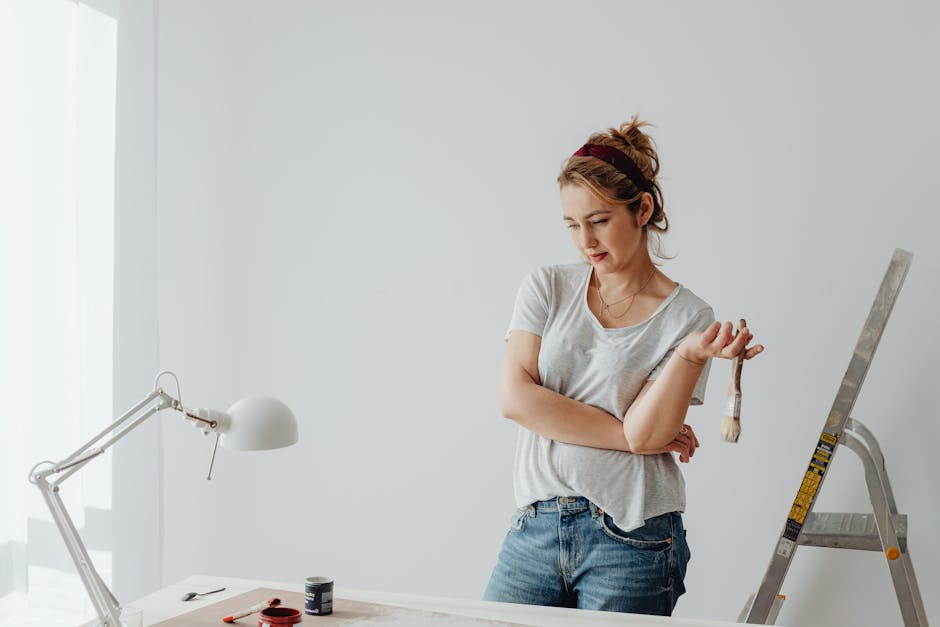 Young woman in casual attire pondering a home DIY project with paintbrush.