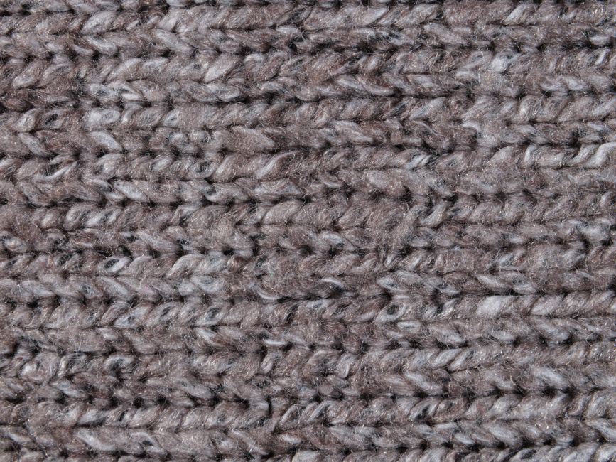 Detailed close-up of a grey knitted wool textile, showcasing intricate patterns and textur