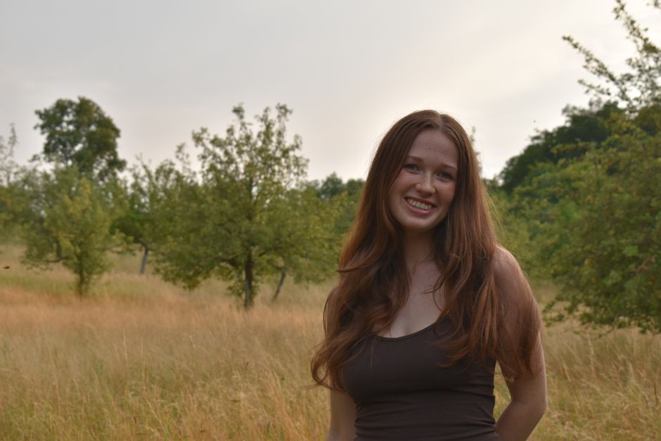 Portrait of a smiling young woman in a lush summer orchard in Bavaria.
