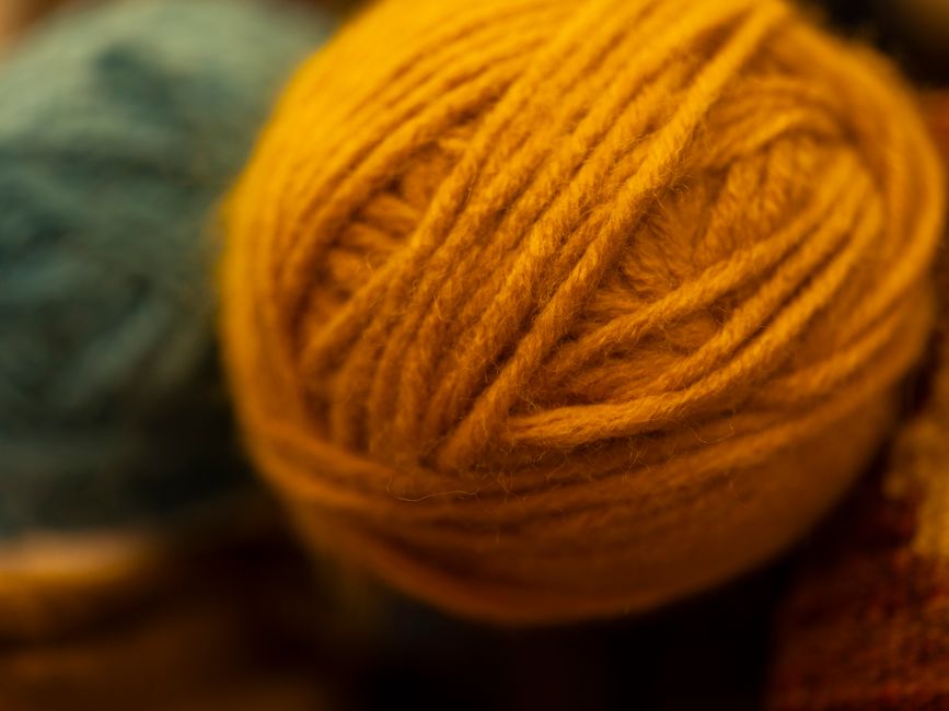 A detailed view of a yellow wool yarn ball, showcasing its texture and warm tone.
