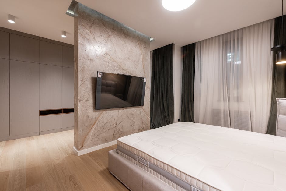 Interior of modern bright house with TV on wall in middle of room near bed and cabinets near windows with curtains