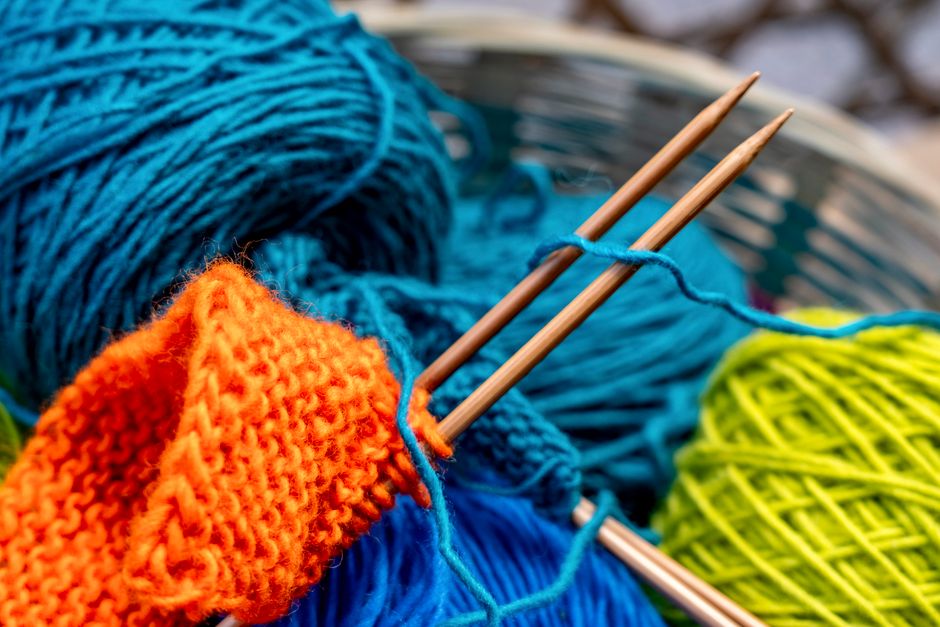 Vibrant yarn balls with knitting needles creating a colorful fabric piece.